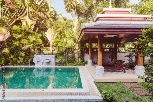Private swimming pool with alcove  sunbeds and exotic palm trees near luxury villa