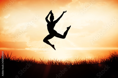Fit brunette jumping and posing against orange sunrise