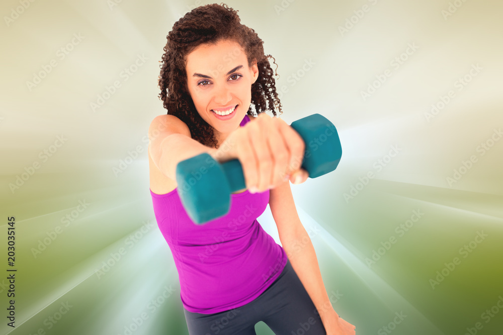 Fit woman lifting blue dumbbell against abstract background