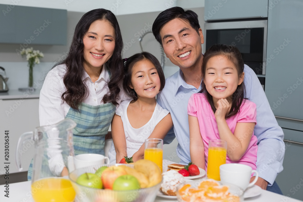 Cheerful family of four enjoying healthy breakfast in kitchen