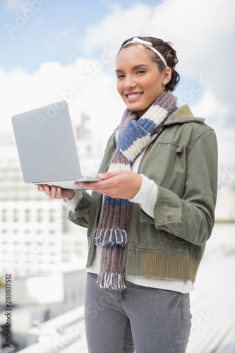 Happy woman standing outside and holding laptop © WavebreakmediaMicro