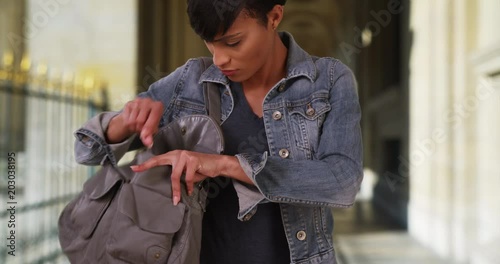 Young black woman looks through her purse for something important in outdoor hallway, Attractive African-American woman digging through her handbag, 4k