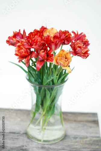 Spring flowers. Bouquet of Red tulips in Glass vase on brown wooden background. Mother s Day and Valentines Day background