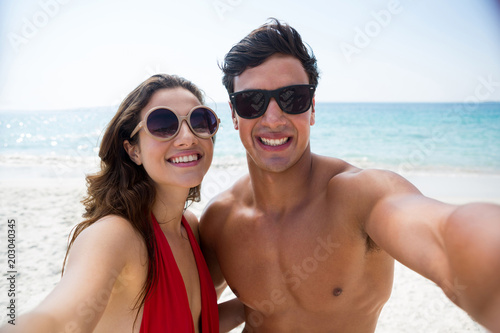 Portrait of couple wearing sunglasses at beach