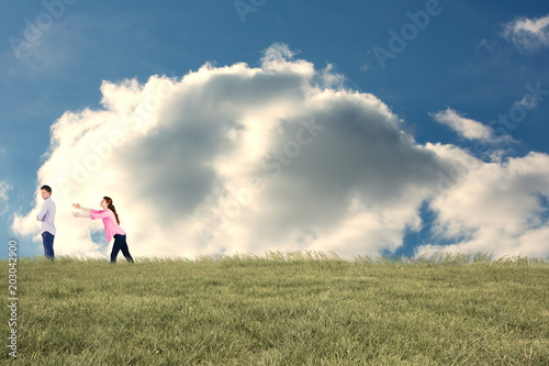 Woman trying to hug man against cloudy sky