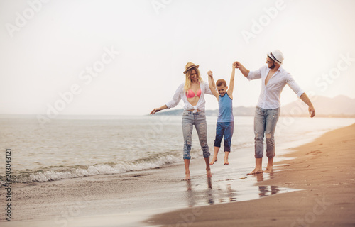 Happy young family have fun on beach run and jump