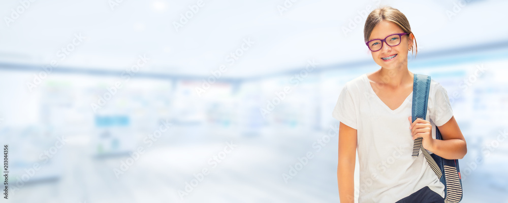 Portrait of modern happy teen school girl with bag backpackand on blurred background.