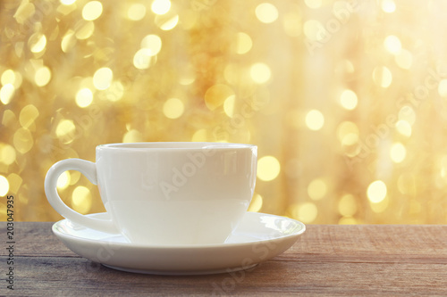 White coffee mug on brown wooden floor and have bokeh light background.