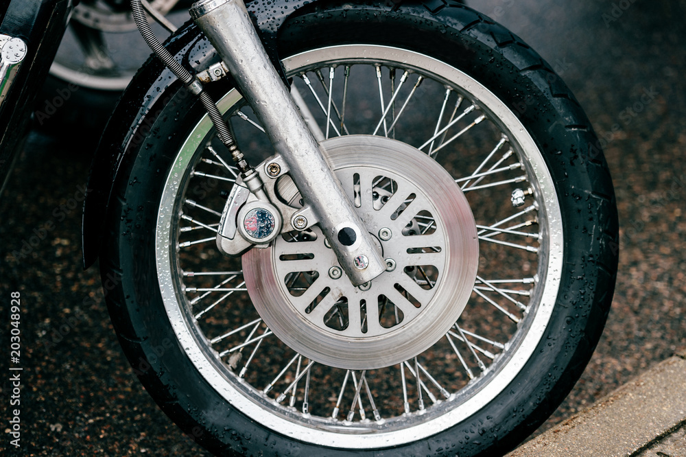 Motorcycle wheel with disk brakes system and metal spokes. Closeup detailed photo of motorbike forks and tire. Different parts of two-wheeled vehicle. Transportation. Modern driving technologies. Motorcycle wheel with disk brakes system and metal spokes. Closeup detailed photo of motorbike forks and tire. Different parts of two-wheeled vehicle. Transportation. Modern driving technologies.