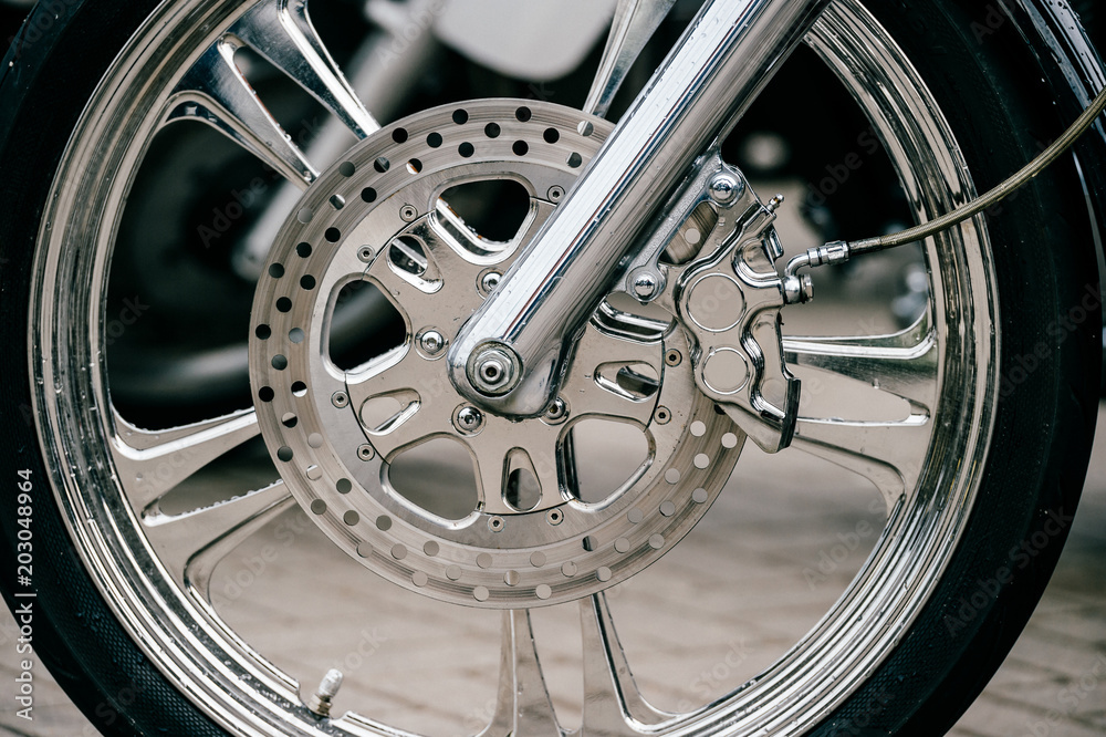 Motorcycle wheel with disk brakes system and metal spokes. Closeup detailed photo of motorbike forks and tire. Different parts of two-wheeled vehicle. Transportation. Modern driving technologies. Motorcycle wheel with disk brakes system and metal spokes. Closeup detailed photo of motorbike forks and tire. Different parts of two-wheeled vehicle. Transportation. Modern driving technologies.