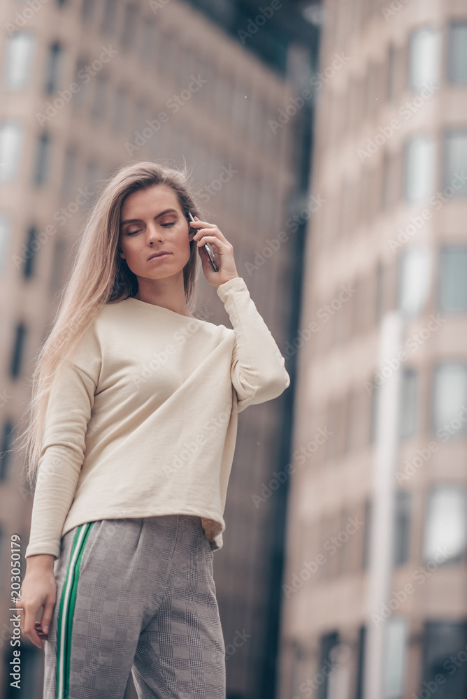 Beautiful woman is having a business conversation by mobile phone near modern office building