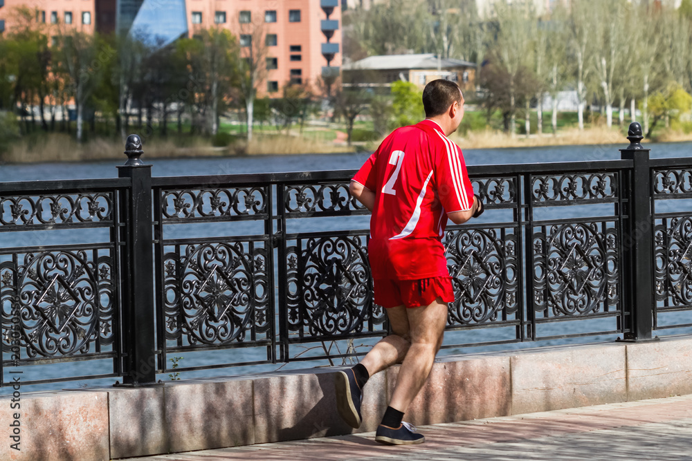 Middle-aged man is running in the park. Back view