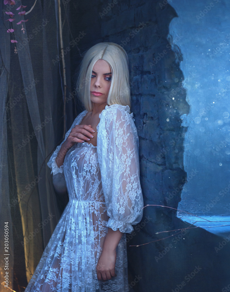 Sexy, gothic, snow queen in a white vintage dress. A blond girl with very  long hair