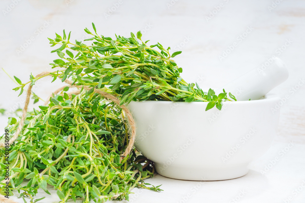 Thyme twigs in the pounder on white wooden table