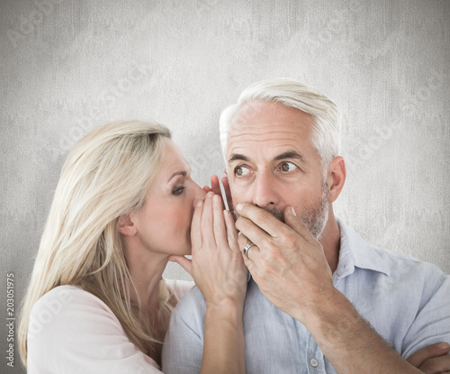 Woman whispering a secret to husband against weathered surface 