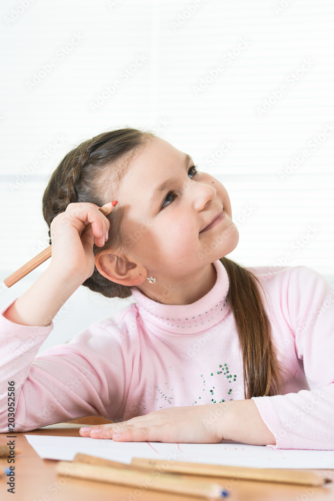 Cute schoolgirl sitting at table and drawing Cute schoolgirl sitting at table and drawing