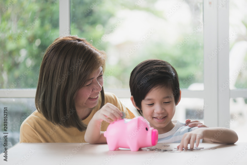 Asian mother and her child putting a coin into a piggy bank Asian mother and her child putting a coin into a piggy bank