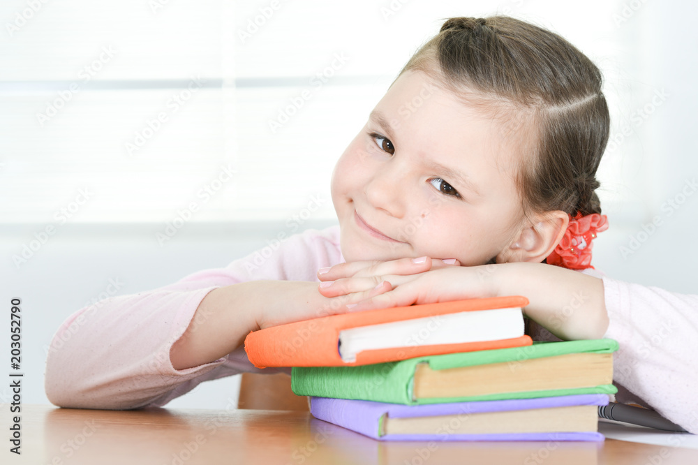 Cute schoolgirl sitting at table and doing homework at home Cute schoolgirl sitting at table and doing homework at home