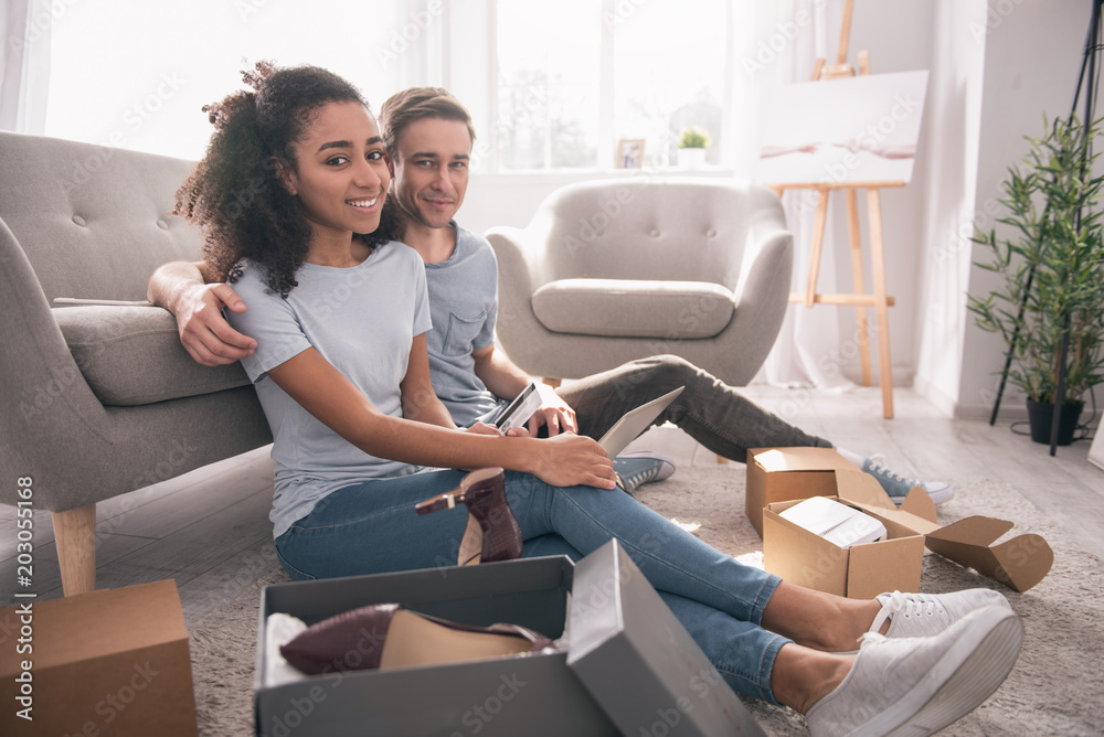 Obraz premium Purchase of things. Nice positive couple sitting together while doing online shopping