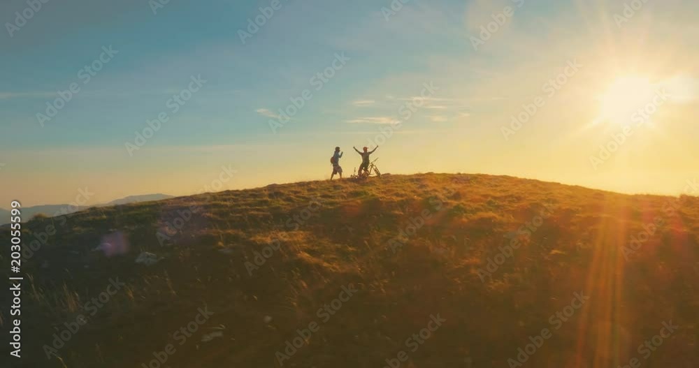 Crane shot of two mountain bikers celebrating on the top in sunset. Crane shot of two mountain bikers celebrating on the top in sunset.