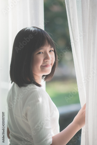 Asian girl opening window curtains Free Download Asian girl opening window curtains - GFXLoad