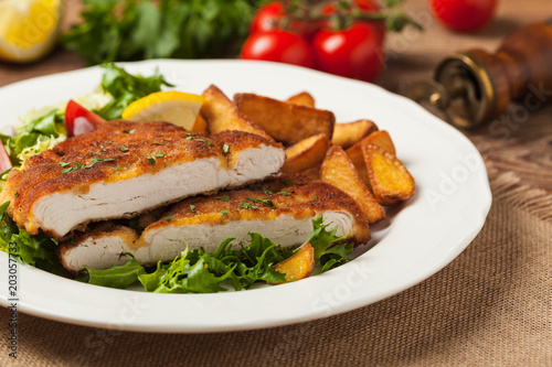 Chicken schnitzel, served with roasted potatoes and salad.