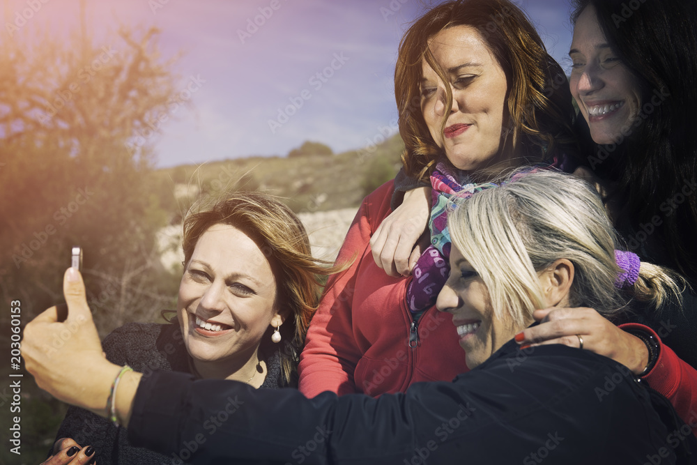 Four women friends are doing a selfie. Nature background. Four women friends are doing a selfie. Nature background.