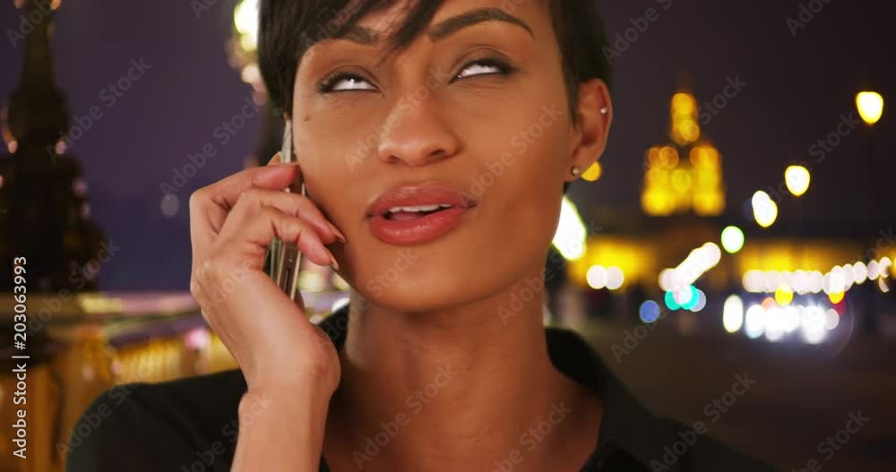 Attractive black woman traveling in Paris on the Pont Alexandre III talks over the phone with someone back home, Black modern beauty describes her fun time in France to her friend over the phone, 4k