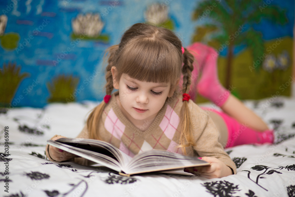 Little cheerful girl read book in bed. Concept of kids knowledge Little cheerful girl read book in bed. Concept of kids knowledge