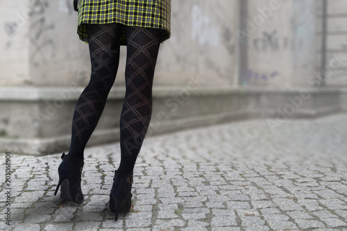 Frau in High Heels, schwarzen Strümpfen und Faltenrock.