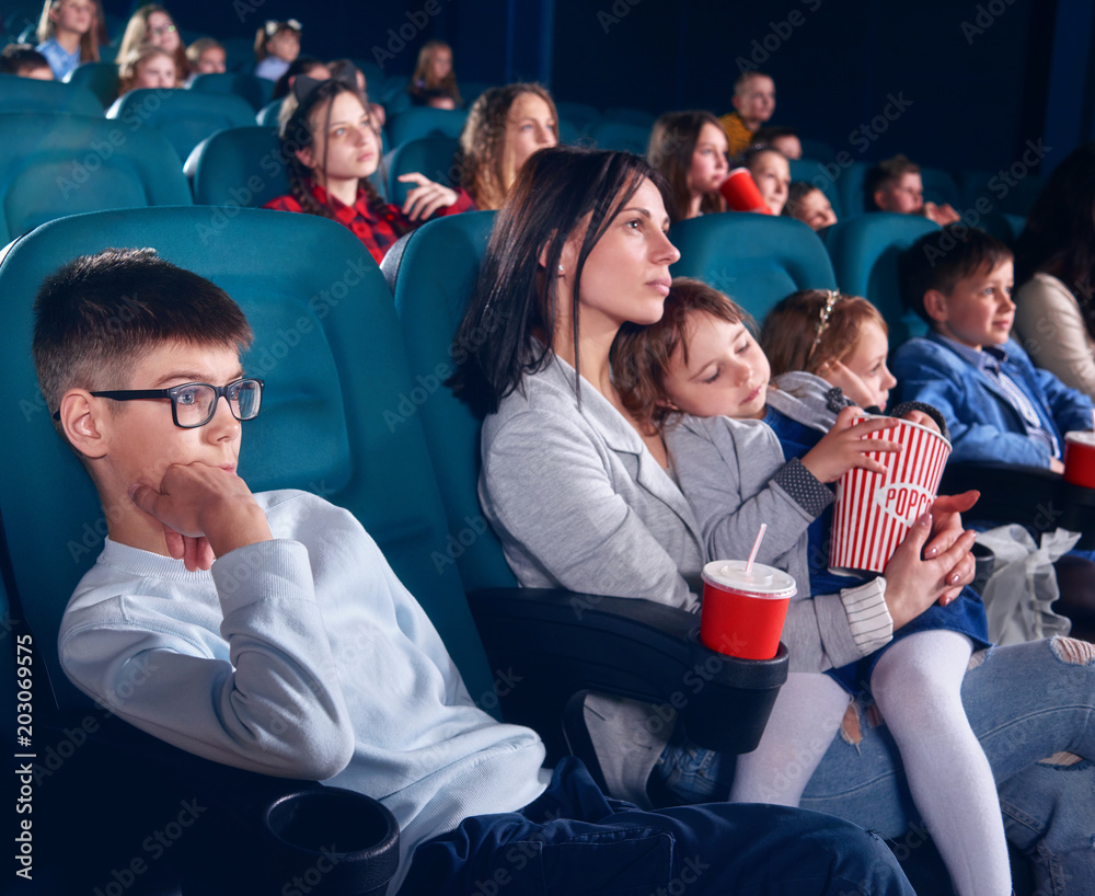 Spectators sitting in comfortable chairs and watching film in cinema ...