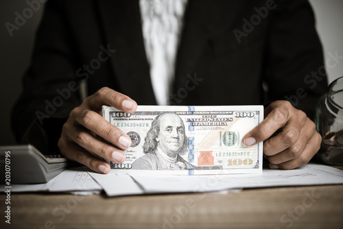 Hands counting dollar banknotes on wooden table