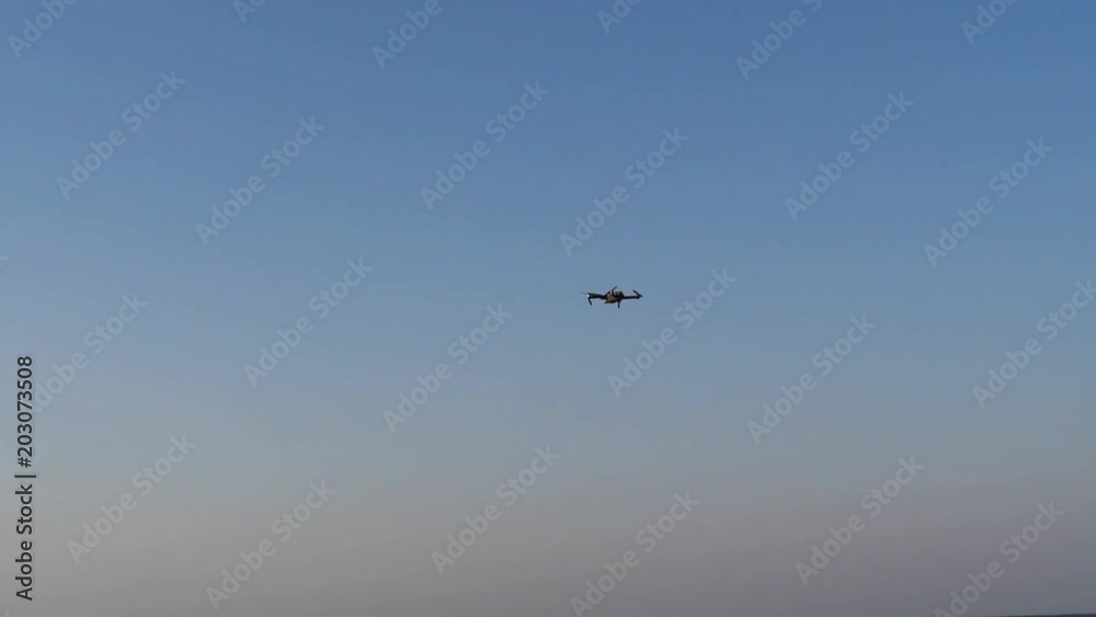 Small drone flying with GPS making a ride over blue sky and following peoples on the beach. Small drone flying with GPS making a ride over blue sky and following peoples on the beach.
