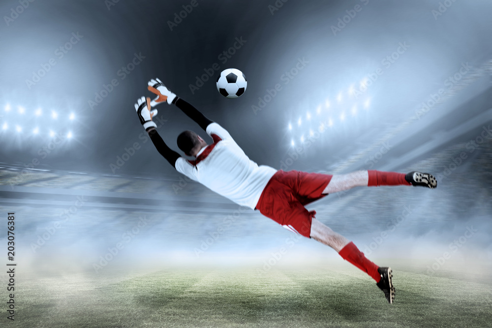 Fit goal keeper jumping up against football stadium Fit goal keeper jumping up against football stadium