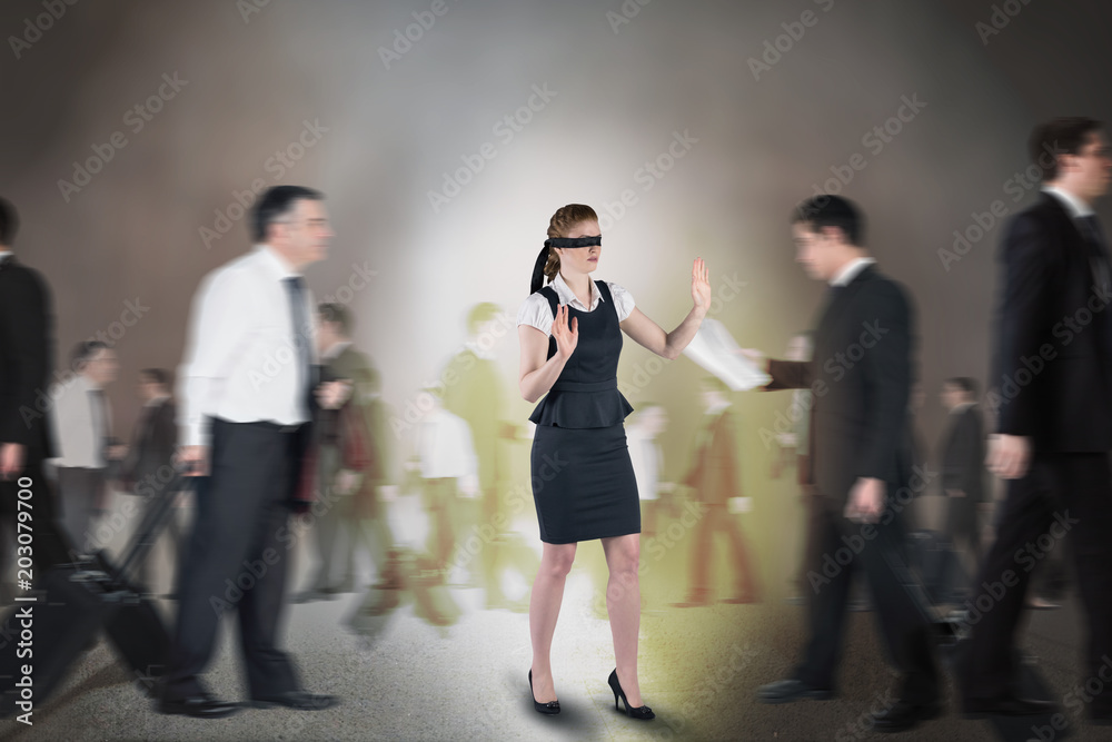Composite image of redhead businesswoman in a blindfold walking through crowd Composite image of redhead businesswoman in a blindfold walking through crowd