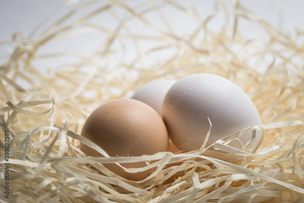 Three chicken eggs lie in a nest of straw, shot close-up Three chicken eggs lie in a nest of straw, shot close-up