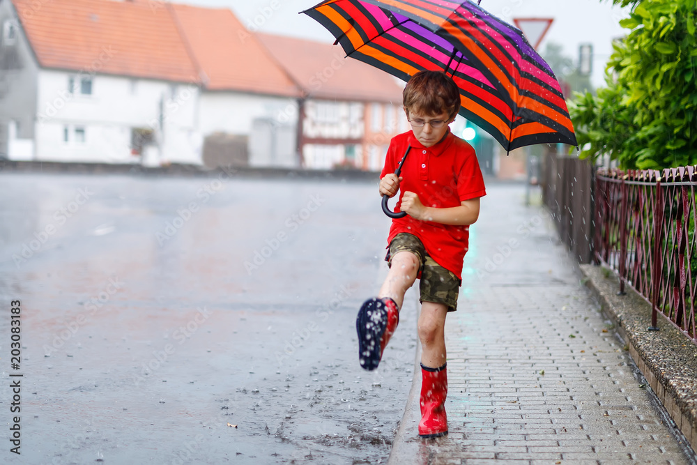 Kid boy wearing red rain boots and walking with umbrella Stock Photo Adobe Stock