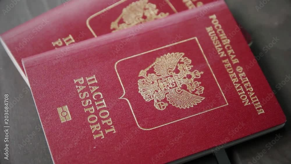 Man's hand puts two international passports on wooden background. Closeup Man's hand puts two international passports on wooden background. Closeup