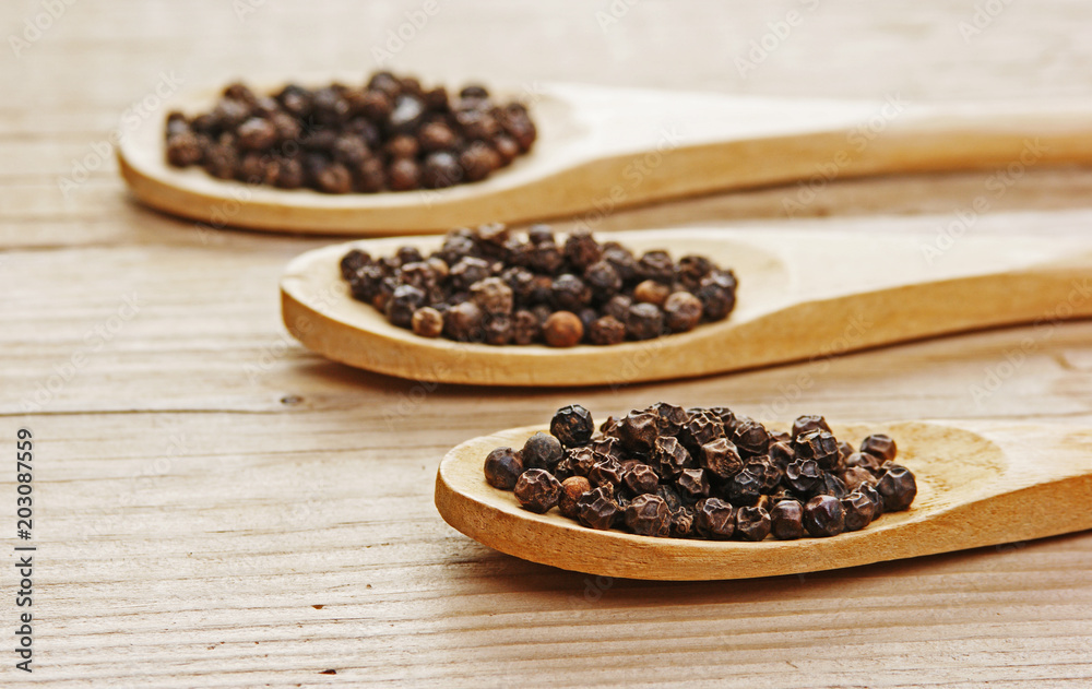 Black pepper in wooden spoon on the old board Black pepper in wooden spoon on the old board
