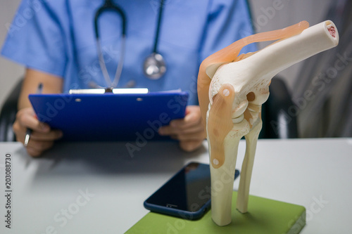 An orthopedic surgeon reads a patient's knee replacement report for analysis and guidelines for postoperative treatment and allows the patient to live a normal life. medical and orthopedic concept.
