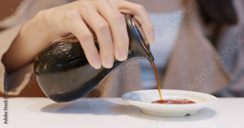 Woman putting soy sauce on plate in Japanese restaurant