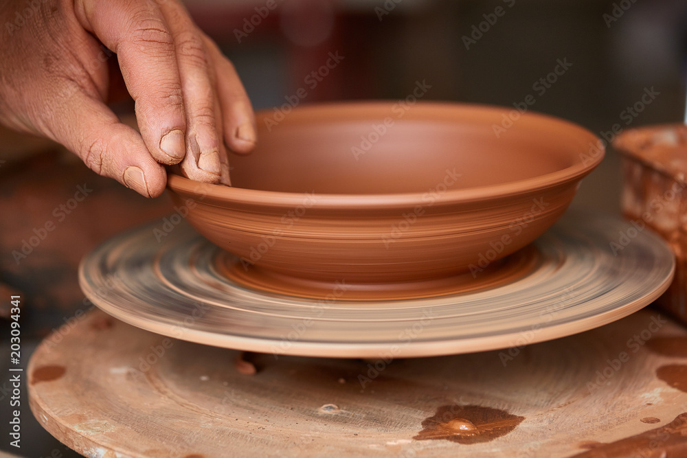 Close-up hands of a male potter in apron molds bowl from clay, selective focus Close-up hands of a male potter in apron molds bowl from clay, selective focus