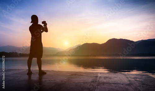 Man traveler taking photos of sunset at mountain and river landscape. © eggeeggjiew