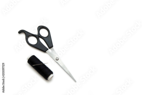 Scissors, needle and sewing thread coil on white background.