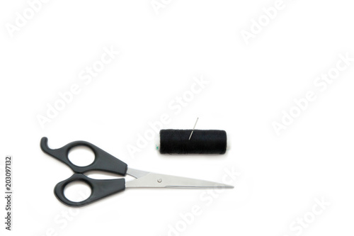 Scissors, needle and sewing thread coil on white background.