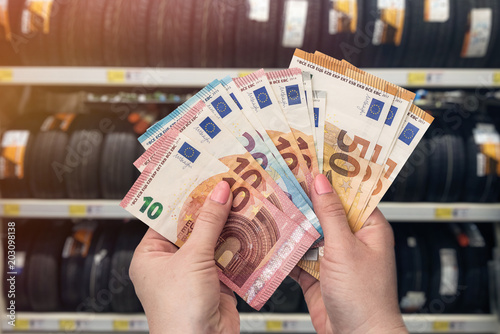 Closeup of hands with euro banknotes in tire shop