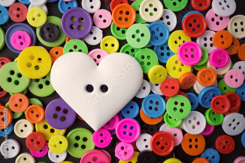big white heart button on mix assorted colors sewing crafts buttons background