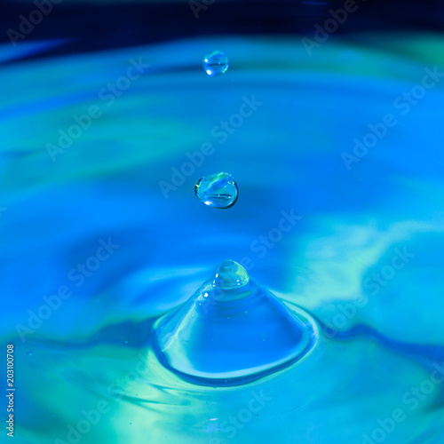 pure water droplet splashing on water surface forming beautiful shapes abstract concept blue hue photo