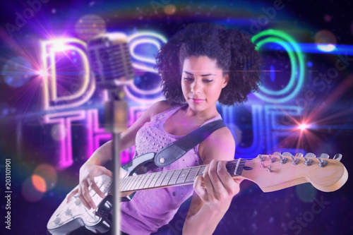 Pretty girl playing guitar against digitally generated colourful discotheque text