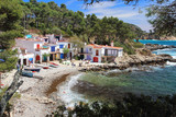 Main view of cala s'Alguer, a lovely beach surrounded by traditional fishermen's white buildings with colorful doors and windows, Palamos, Costa Brava, Spain.